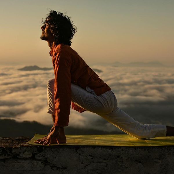 Silhouette of a man in a balancing pose against a sunrise.